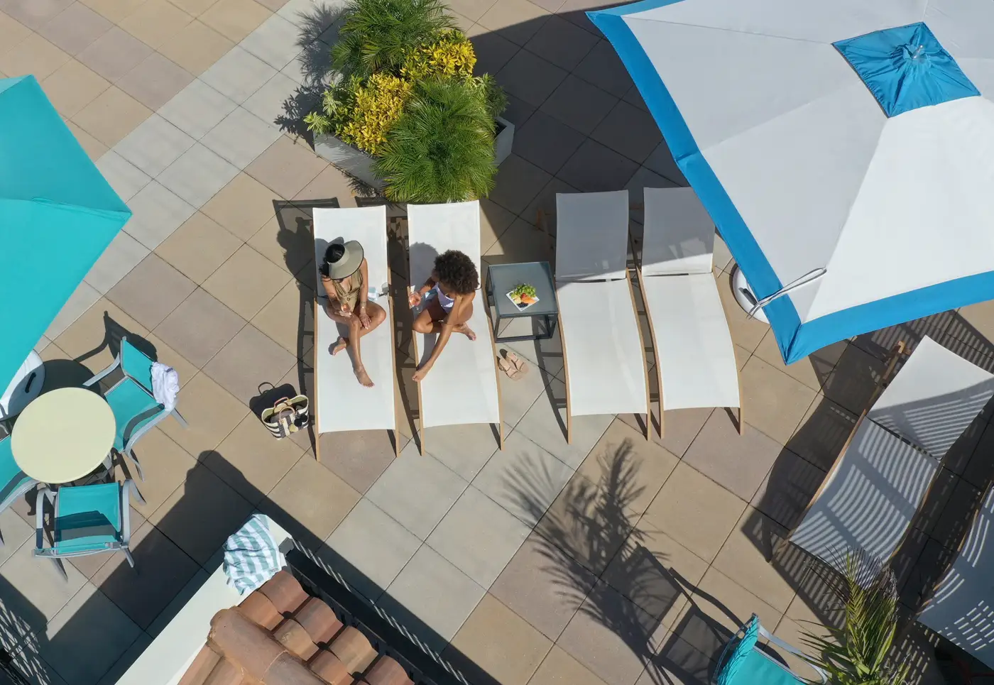 Women in chairs with drinks by pool